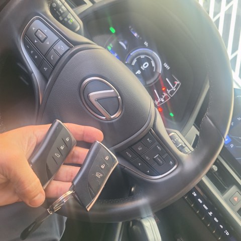 Par de chaves presenciais de Lexus recém-programadas, seguradas junto ao volante do veículo.