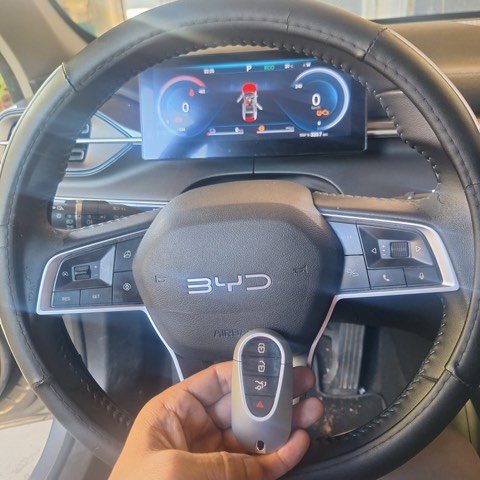 Chave presencial de BYD elétrico programada no local, segurada junto ao volante.