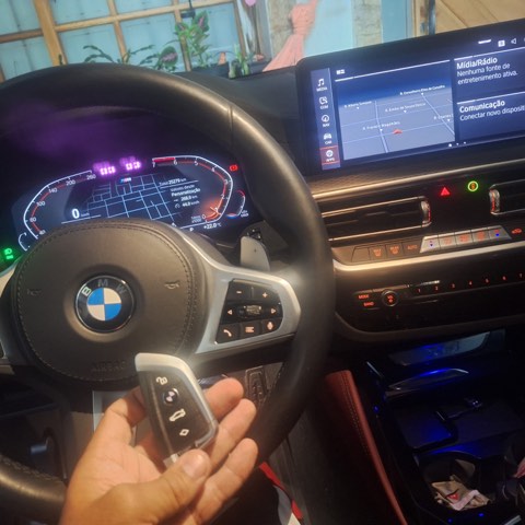 Chave presencial de BMW Série 3 programada dentro do veículo, com painel digital ligado ao fundo.
